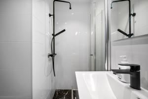 baño blanco con ducha y lavamanos en Stay Bryggen - Serviced apartments in the city center, en Bergen