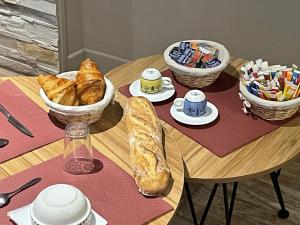 uma mesa de madeira com uma mesa com pão e pastelaria em Villa Kiara Hébergements em Cusset