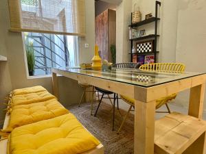 a dining room with a glass table and yellow chairs at OIKIASTUDIOS2 in Patra