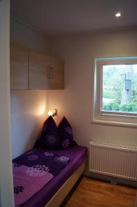 a small bedroom with a purple bed and a window at Mobilheim und Blockhaus mit Seeblick in Sternberg
