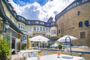 un patio del hotel con mesas y sombrillas frente a un edificio en Hotel Der Achtermann, en Goslar