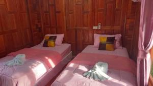 twee bedden naast elkaar in een kamer bij กอบสุข รีสอร์ท 2 k11 in Ban Ton Liang