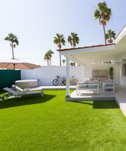 a backyard with green grass and an umbrella at Aquarium Bungalow private jacuzzi, 3 bedrooms, AC and Bikes in Maspalomas