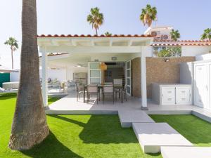 um pátio com uma mesa e cadeiras sob uma pérgola em Aquarium Bungalow private jacuzzi, 3 bedrooms, AC and Bikes em Maspalomas