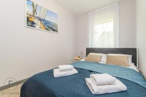 a bedroom with a blue bed with towels on it at Flatbook Apartamenty - Jantar Park in Jantar