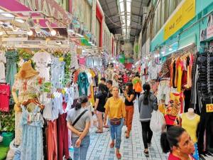 a group of people walking through a market with clothes at Miracle Gallery Hotel in Makkasan