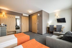 um quarto de hotel com uma cama, um sofá e uma mesa em Hotel Leśny em Bialystok