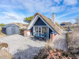 a thatch roofed cottage with a patio at Holiday home Henne CXXVIII in Henne Strand