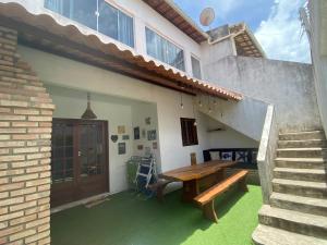 Cabana dos Milagres aconchegante a 150m da praia e WI FI في ساو ميغيل دوس ميلاجريس: منزل مع طاولة خشبية في الفناء