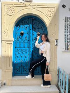 a woman standing in front of a blue door at Dar Lilia Monastir in Monastir