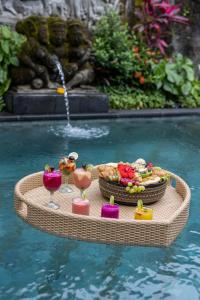 una mesa en el agua con comida y bebida en The Gardener's Cottage, en Ubud