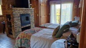 1 dormitorio con 2 camas y chimenea de piedra en Casa de Montaña Valle Escondido en San Martín de los Andes