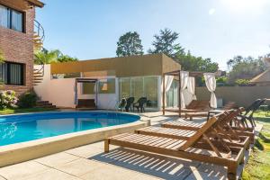 a swimming pool with chairs and a house at Costanera Hotel in Villa Carlos Paz