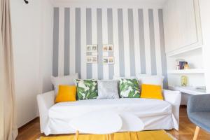 a living room with a white couch with colorful pillows at Retropolitan Living Patras in Patra