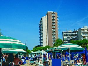 a beach with blue chairs and umbrellas and a building at Flat in Lignano Sabbiadoro in Lignano Sabbiadoro