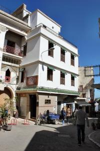 a white building with people walking in front of it at Hotel Maram in Tangier