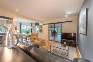 a living room with a leather couch and a television at ST JORIOZ-Maison spacieuse avec PISCINE et Vue, LLA Selections by Location lac Annecy in Saint-Jorioz