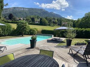 a backyard with a swimming pool and a wooden deck at ST JORIOZ-Maison spacieuse avec PISCINE et Vue, LLA Selections by Location lac Annecy in Saint-Jorioz