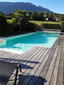 a blue swimming pool with a wooden deck at ST JORIOZ-Maison spacieuse avec PISCINE et Vue, LLA Selections by Location lac Annecy in Saint-Jorioz