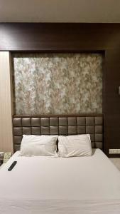 a bed with white sheets and pillows in a bedroom at Hotel Sarovar Residency in Boisar