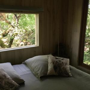 Bett in einem Zimmer mit Fenster in der Unterkunft cabane lodge avec spa privatif in Livernon