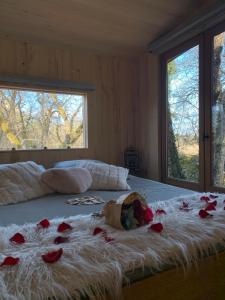 uma cama com rosas com duas janelas em cabane lodge avec spa privatif em Livernon