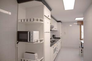 a kitchen with white cabinets and a microwave on a wall at Apartamento en Sigüeiro Rúa do Tambre in Sigüeiro