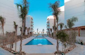 einem Pool mit Palmen vor einem Gebäude in der Unterkunft Porto Said Tourist Resort Luxury Hotel Apartment no390 in `Ezbet Shalabi el-Rûdi