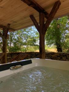 una bañera con agua bajo un techo de madera. en cabane lodge avec spa privatif en Livernon