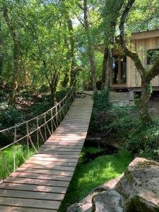 un puente de madera sobre un estanque en un jardín en cabane lodge avec spa privatif, en Livernon