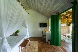 a bedroom with a bed with a green and white curtain at Pousada Outeiro in Praia do Espelho