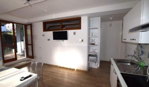 坎普碼港的住宿－Casa Tua，一间铺有木地板的白色墙壁厨房以及一台电视