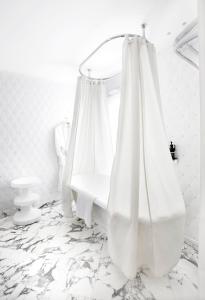 a white room with a bed with a shower curtain at Hôtel Thoumieux in Paris