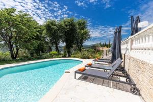 a swimming pool with two lounge chairs and an umbrella at Maison Saint Paul in La Colle-sur-Loup