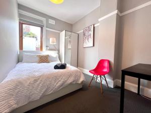 a bedroom with a bed and a desk and a red chair at Coco’s Abode in Sydney