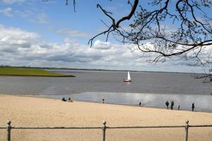 - un voilier dans l'eau avec des personnes sur la plage dans l'établissement Ferienhaus Wattwurm 1, FeWo Vermittlung Nordsee, à Dangast