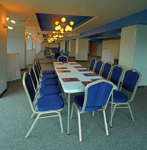 a conference room with a long table and blue chairs at Hotel Rila in Dupnitsa