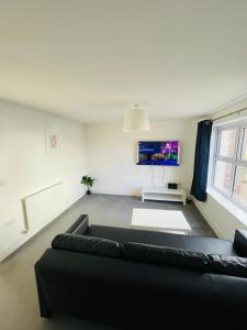 uma sala de estar com um sofá preto e uma televisão em Anox serviced apartment em Newcastle upon Tyne