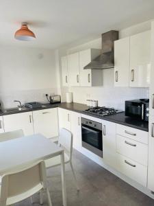 a kitchen with white cabinets and a table and a stove at Anox serviced apartment in Newcastle upon Tyne