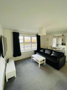 uma sala de estar com um sofá preto e uma mesa em Anox serviced apartment em Newcastle upon Tyne