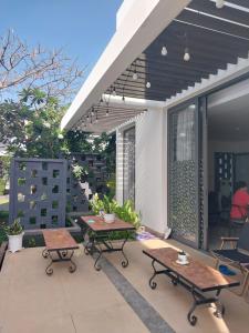 un patio con mesas, sillas y toldos en Oceanami Resort & Beach Club, en Long Hai