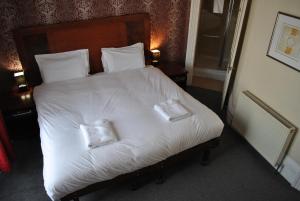 1 dormitorio con 1 cama blanca y 2 almohadas en Town House Rooms, en Hastings