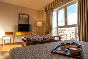 a hotel room with a tray of food on a bed at Sercotel Avenida Almería in Almería