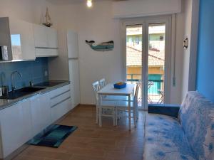 uma cozinha com uma mesa e um sofá e uma cozinha com vista em VELA vicino al mare BluDiPietraLigure em Pietra Ligure