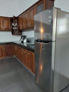 - un réfrigérateur en acier inoxydable dans une cuisine avec des placards en bois dans l'établissement Comfy Home near the town, à Maharagama