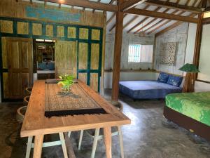 Villa Nextdoor Nature Yogyakarta في بانتول: غرفة مع طاولة خشبية وسرير