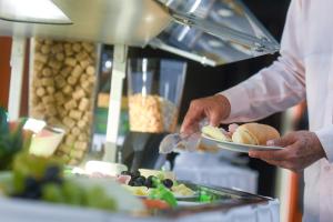 a person holding a plate of food in a kitchen at Like U Hotel Brasília in Brasilia