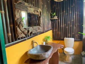 a bathroom with a stone sink and a toilet at Villa Nextdoor Nature Yogyakarta in Bantul