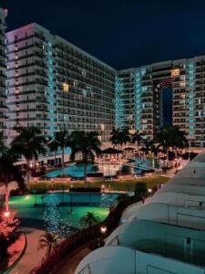 a view of a large building with a pool at night at SHELL RESIDENCE C9 NEAR AIRPORT & MALL OF ASIA in Manila