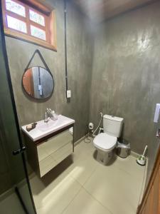 a bathroom with a toilet and a sink and a mirror at Chalé Ubá in Novo Airão